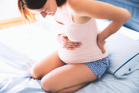 A pregnant woman on a bed with back pain