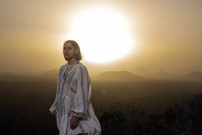 Beth, CDU indigenous student standing on a hill with a sunset backdrop