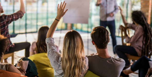 Students in a classroom raising their hands to ask a question