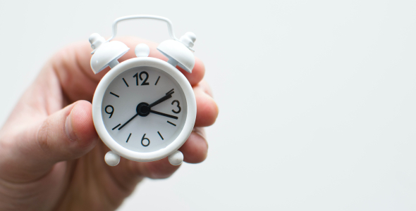 Hand holding clock to represent time management