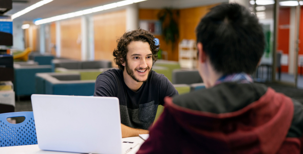 CDU student Nicholas in the library with a study buddy