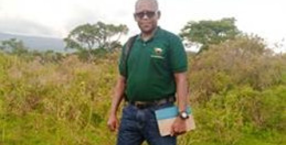 Juma Kegamba standing in field with trees in background