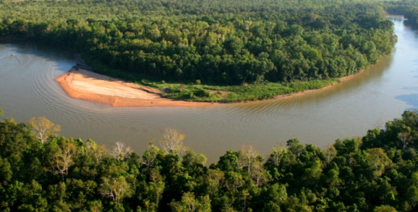 Aerial view of the bend in a river surrounded by dense forest