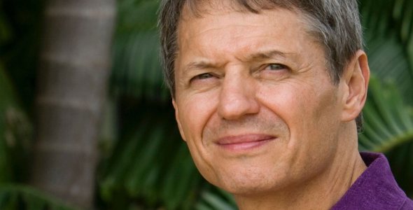 Keith Christian head and shoulders with palm tree trunk and large green leaves in the background