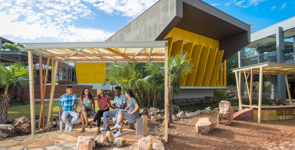 a group of students sitting and a bench at casuarina campus