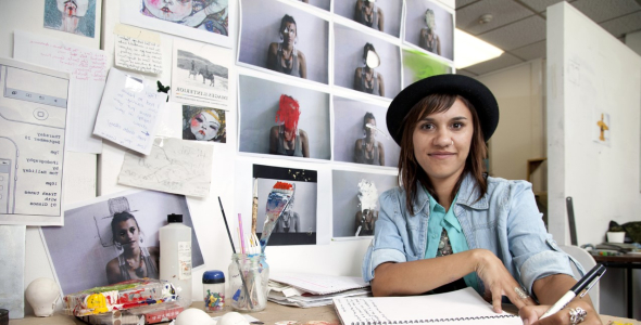 girl with black hat doing art work at table