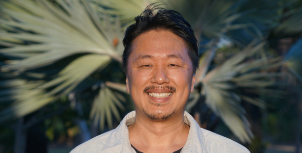 Yusuke Fukuda head and shoulders, with out of focus palm fronds in the background