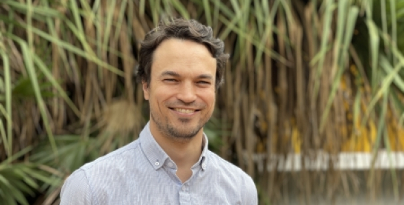 Dr Clement Duvert, head and shoulders, with green spiky-looking leaves hanging down in background