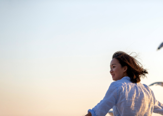 Female student looking back at the camera smiling, while seaguls fly near her