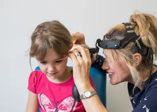 Child receiving ear examination by doctor