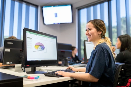 Female student at a computer looking at a spreadsheet
