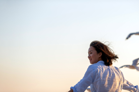 Female student looking back at the camera smiling, while seaguls fly near her