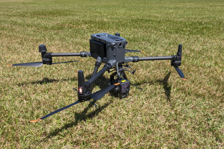 black drone with 4 rotors standing on short green grass