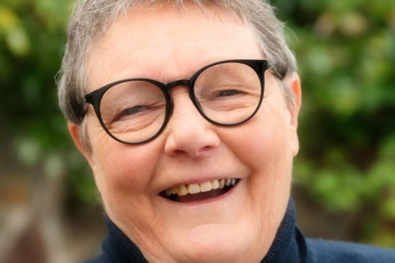 Professor Helen Verran Smiling in front of green trees