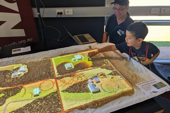 Miguel teaches kids how to use the fire simulation game at CDU open day 2023