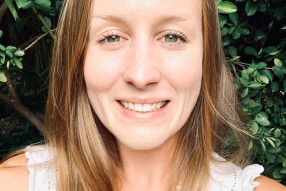 Staff portrait of Hayley Geyle young women with light brown hair smiling in front of trees