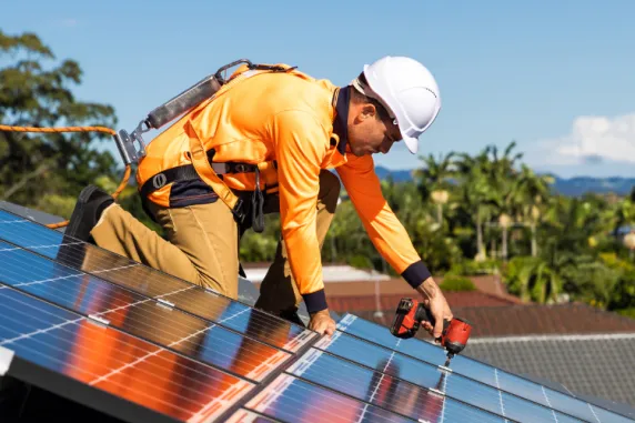 Man installs solar panel on roof in tropical suburb
