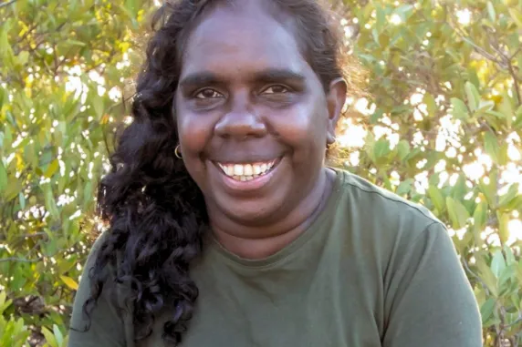 Balanydjarrk smiling in green shirt in front of mangrove leaves