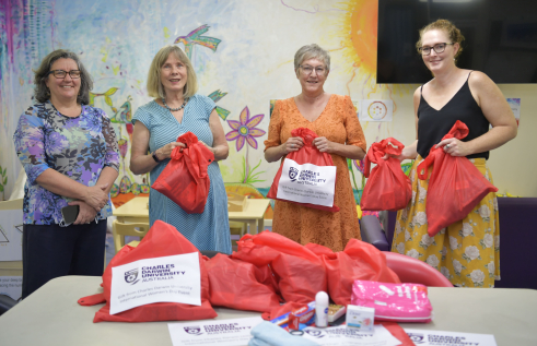 Territory Families, Housing and Communities Deputy CEO Jeanette Kerr, CDU Secretary Professor Hilary Winchester AM, Executive Officer Susan Crane and TFHC Director of Housing Pathways Emma Clee present donated essential goods to women’s refuges.
