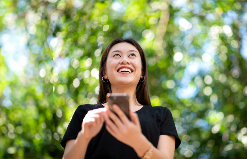 Female with smart phone, green foliage background