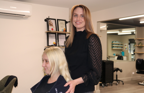 Hairdresser stands over her client