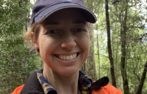 Anna Richards wearing CSIRO cap and high vis vest, with tall trees in background