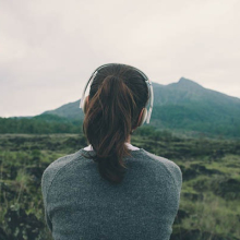 Female wearing headphones gazing into the distance overlooking a mountain