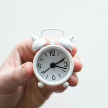 Hand holding clock to represent time management