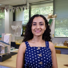 CDU student Nancy Soliman standing in the drafting studio in front of a model building.