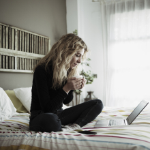 Stock image of female student studying online on her bed with a laptop