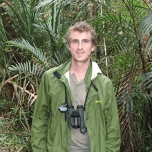 Simon Mahood with binoculars around his neck and palms in the background