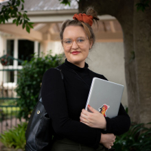 CDU student Claire Bowditch with laptop in front of her home