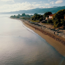 Aerial view of beach with people and boats, mountains in background