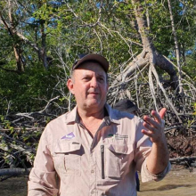 Dr Ben Brown standing in water with mangrove trees behind