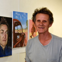 Art teacher Henry Smith inspects some of the paintings in the end-of-year exhibition.